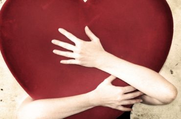 A person embracing a large red heart