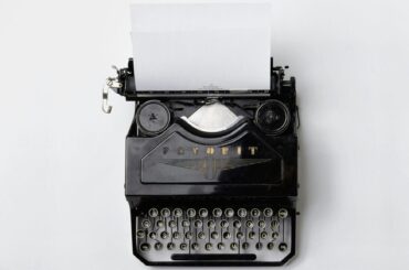 A vintage black typewriter loaded with a blank sheet of paper